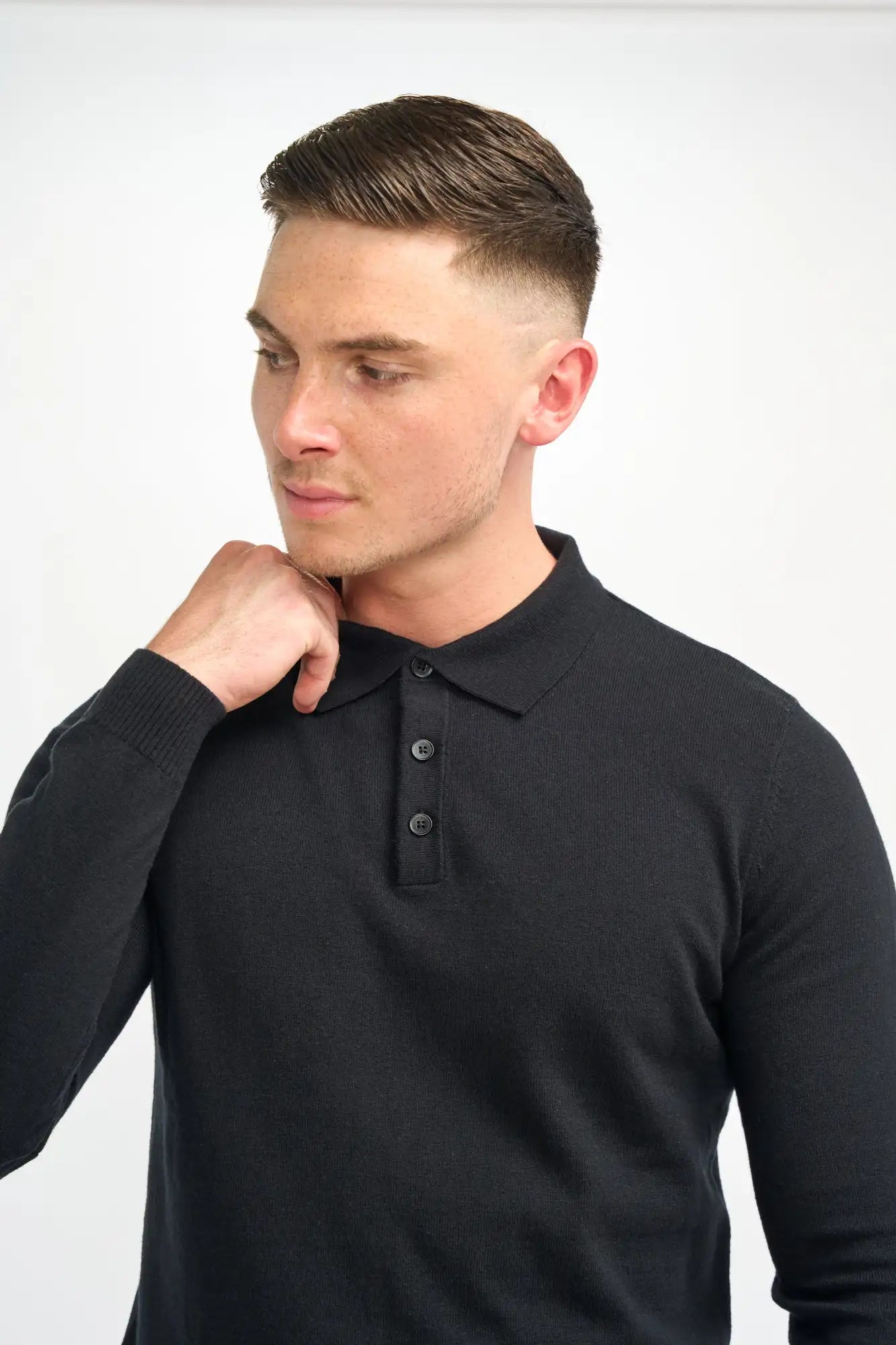 Polo en tricot noir à manches longues avec col côtelé et patte de boutonnage à trois boutons.